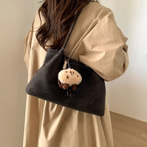 Detail of vintage matte brown tote bag featuring contrast stitching and plush animal charm