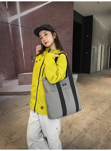 Gray canvas tote bag with black straps worn by model for high-capacity daily commuting