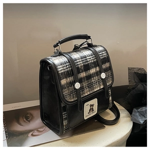 Detail of British style black and white tweed crossbody bag with bear label and leather handle