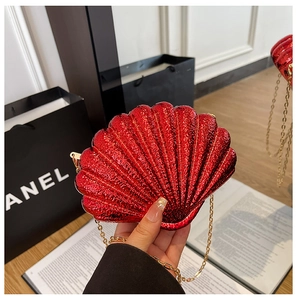 Detailed view of red acrylic shell clutch bag with gold chain strap and glitter finish