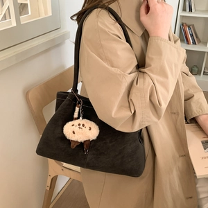 Dark suede shoulder bag with contrast stitching and fuzzy bear paw charm detail