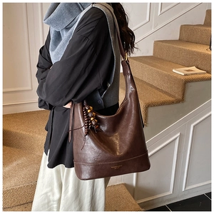 Detailansicht der dunkelbraunen Vintage-Beuteltasche mit Holzperlen und Lederstruktur