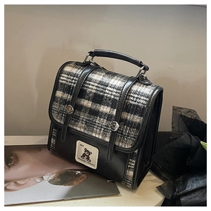 Detail of British style plaid backpack with bear patch and dual-strap closure