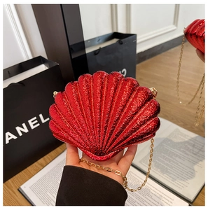 Detail of red shell-shaped evening clutch bag with glossy finish and gold metal chain