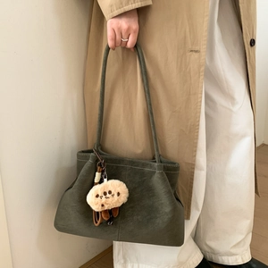 Detailed close-up of dark green matte shoulder bag with plush cookie pendant charm