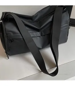 Close-up of wide woven shoulder strap and waterproof nylon fabric on black crossbody bag