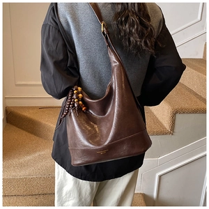 Dunkelbraune Retro-Schultertasche mit Holzperlen-Quaste in einem stilvollen Innenbereich