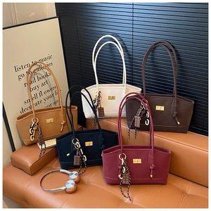 Detail view of five luxury oil wax leather tote bags with silk scarves and charms on a sofa