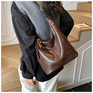 Details der braunen Vintage Hobo-Tasche mit Holzperlen-Anhänger und Goldbeschriftung