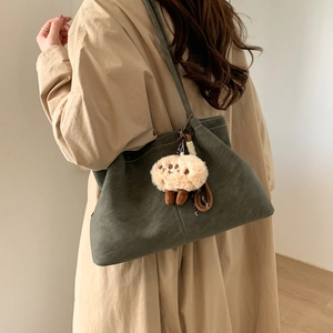 Detail of dark green matte shoulder bag with white contrast stitching and plush charm