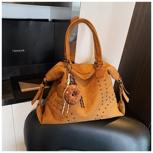 Detailansicht der braunen Wildledertasche mit Wellen-Nieten und Donut-Anhänger-Dekor