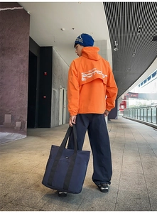 Macro view of the high-capacity orange outdoor jacket with printed logo and blue tote bag