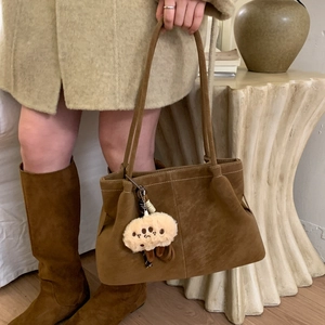 Detailed texture of brown matte shoulder bag featuring a cute plush pendant and side pleats
