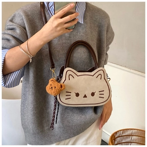 Dettaglio della borsa a gatto in pelle scamosciata bianco crema con manici in pelle marrone