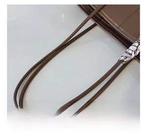 Detail of dark brown leather tote handle with decorative silk scarf and precision stitching