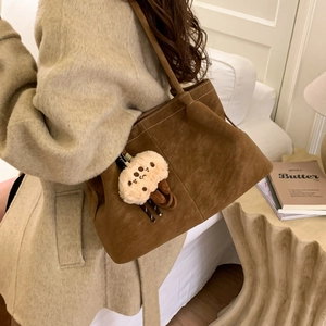 Brown suede tote bag detail with contrast stitching and plush doll charm accessory