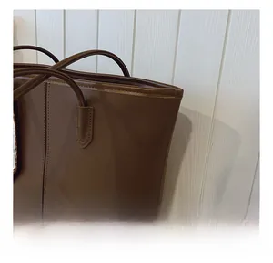 Detailed view of brown leather tote bag with fine stitching and embossed logo