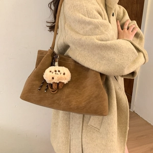 Close-up of brown matte suede tote bag with cute plush biscuit charm accessory