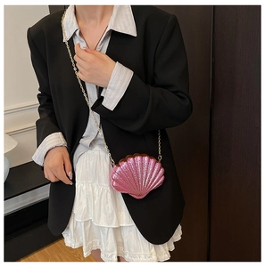 Detail showing the pink shell-shaped evening bag with a metallic glitter finish and chain