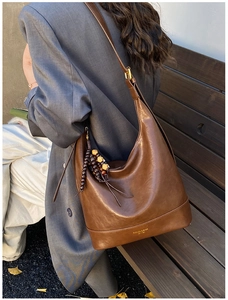 Detail der braunen Vintage-Beuteltasche mit Goldschrift und dekorativen Holzperlen