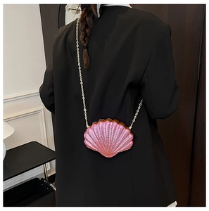 Detail of pink seashell acrylic evening bag with gold chain strap worn on black suit