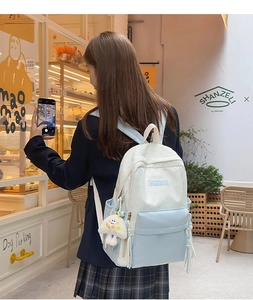 Detail of blue and white contrast backpack with cute plush ghost charm and padded straps