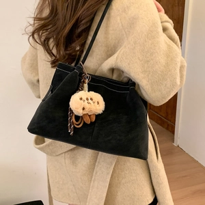 Detail of vintage matte black shoulder bag with white stitching and plush charm