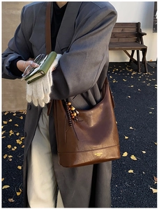 Detail der dunkelbraunen Leder-Eimertasche mit Vintage-Holzperlen und Logo-Schriftzug