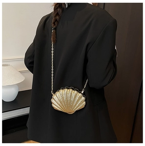 Detail of gold shell-shaped evening bag with radial texture and metal chain on model