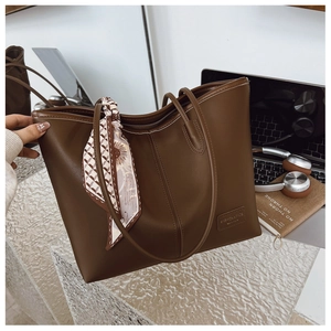Détail d'un grand sac cabas en cuir marron avec foulard sur un bureau moderne