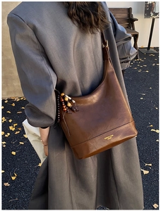 Nahaufnahme der braunen Vintage-Ledertasche mit bunten Perlenanhängern und Golddruck