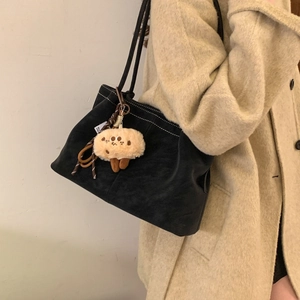 Detail of black matte shoulder bag with white contrast stitching and plush biscuit charm