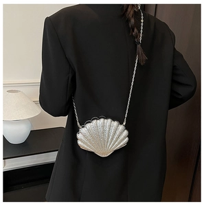 Macro detail of silver shell-shaped evening bag with radiant pleated texture and metal chain
