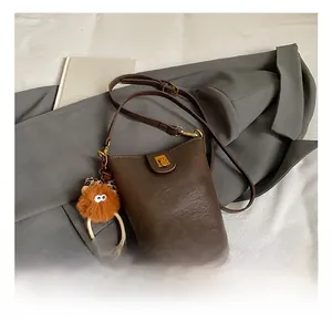 Detail of dark brown vintage bucket bag with HOCOMU logo and plush eye charm accessory