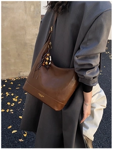 Nahaufnahme braune Vintage-Ledertasche mit Holzperlen-Quaste und modischem Logo-Schriftzug