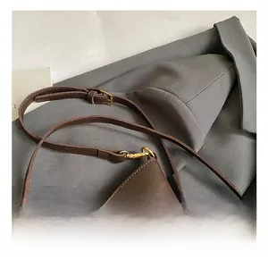Detail of dark brown lychee grain leather crossbody bag with adjustable strap and gold buckle