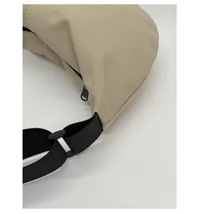 Close-up of beige nylon crossbody bag featuring black contrast zipper and woven strap