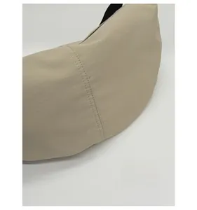 Close-up of beige crescent bag featuring durable fabric and vertical double stitching