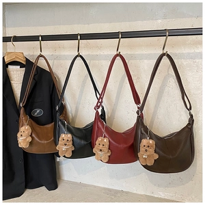 Detail of four large hobo tote bags in brown, black, and red with teddy bear charms