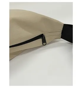 Close-up of smooth metal zipper and durable nylon fabric on beige crossbody bag