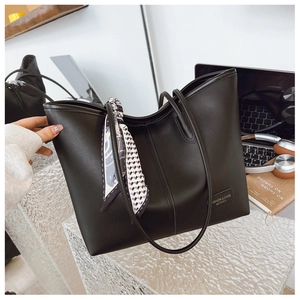 Détail d'un cabas noir en similicuir avec foulard en soie et plaque métallique mode