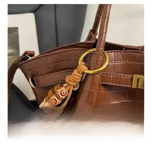 Dettaglio borsa marrone motivo coccodrillo con hardware dorato e charm di perle