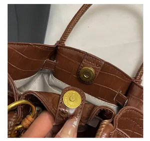 Dettaglio borsa tote in ecopelle marrone con chiusura magnetica dorata e fodera interna
