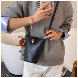 Detailed view of black leather bucket bag featuring gold buckle and plush leopard charm