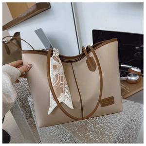 Détail d'un sac cabas beige avec bordure marron et foulard décoratif sur un bureau