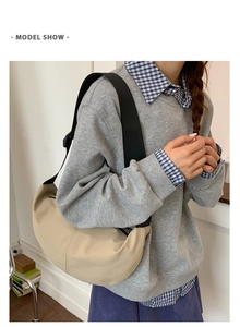 Detail of beige crescent crossbody bag with adjustable black shoulder strap and metal zipper