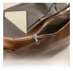 Close-up detail of silver zipper on a brown leather bag with classic herringbone lining