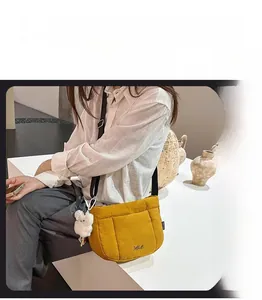 Vue détaillée du sac bandoulière matelassé jaune avec breloque en peluche blanche