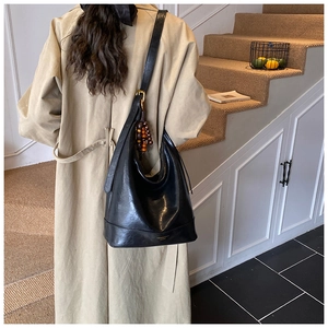 Details einer schwarzen Hobo-Tasche aus Leder mit goldener Hardware und Holzperlen