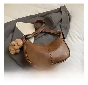 Detail of brown matte leather tote bag featuring white contrast stitching and puppy charm